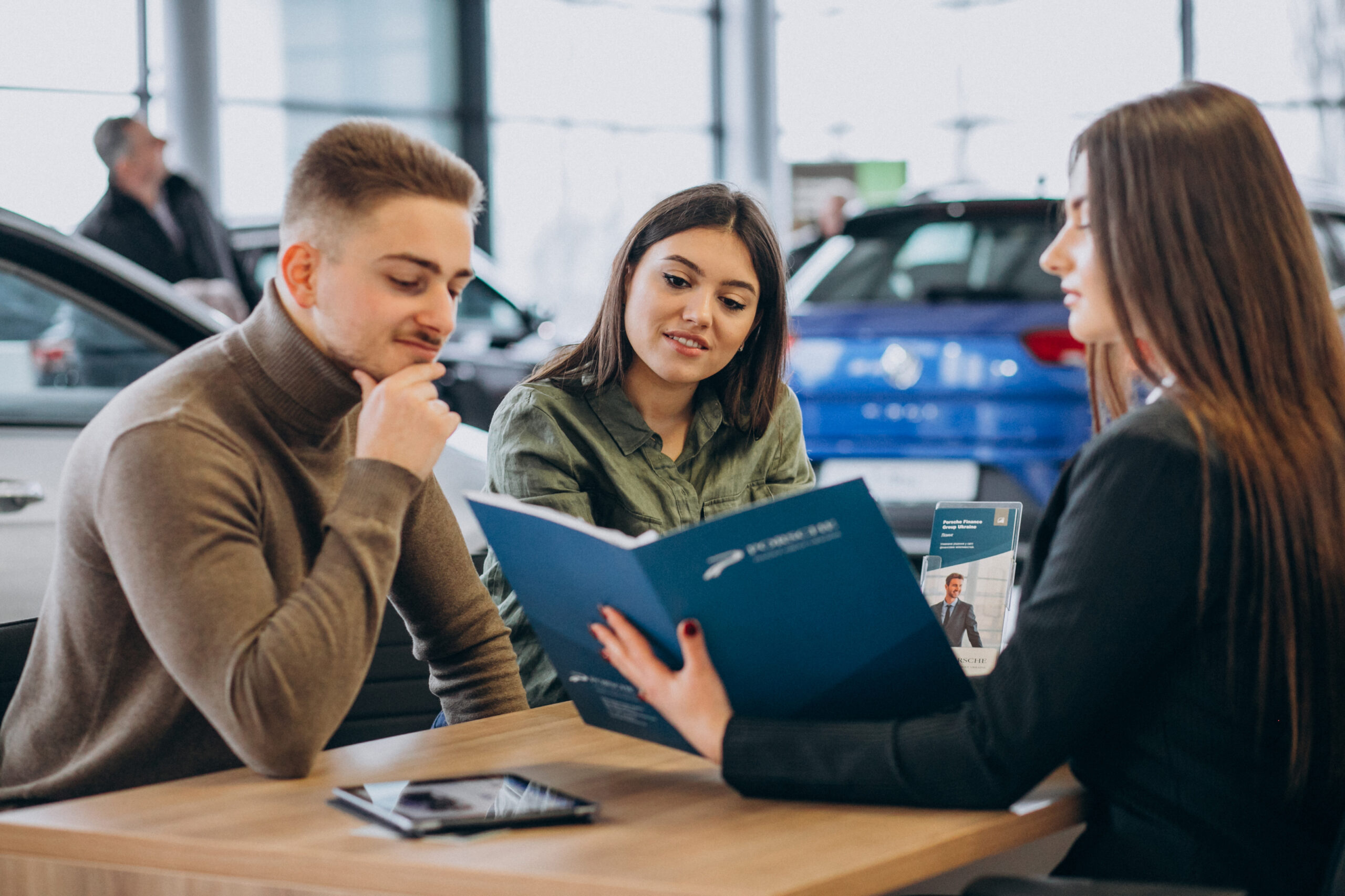 young couple talking sales person car showroom scaled