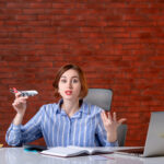 front view travel agent sitting her working place playing with toy plane agency service assistant manager map operator global world ticket